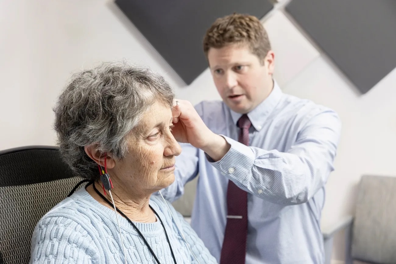 Dr. Kleckner placing a hearing test sensor behind a patient's ear